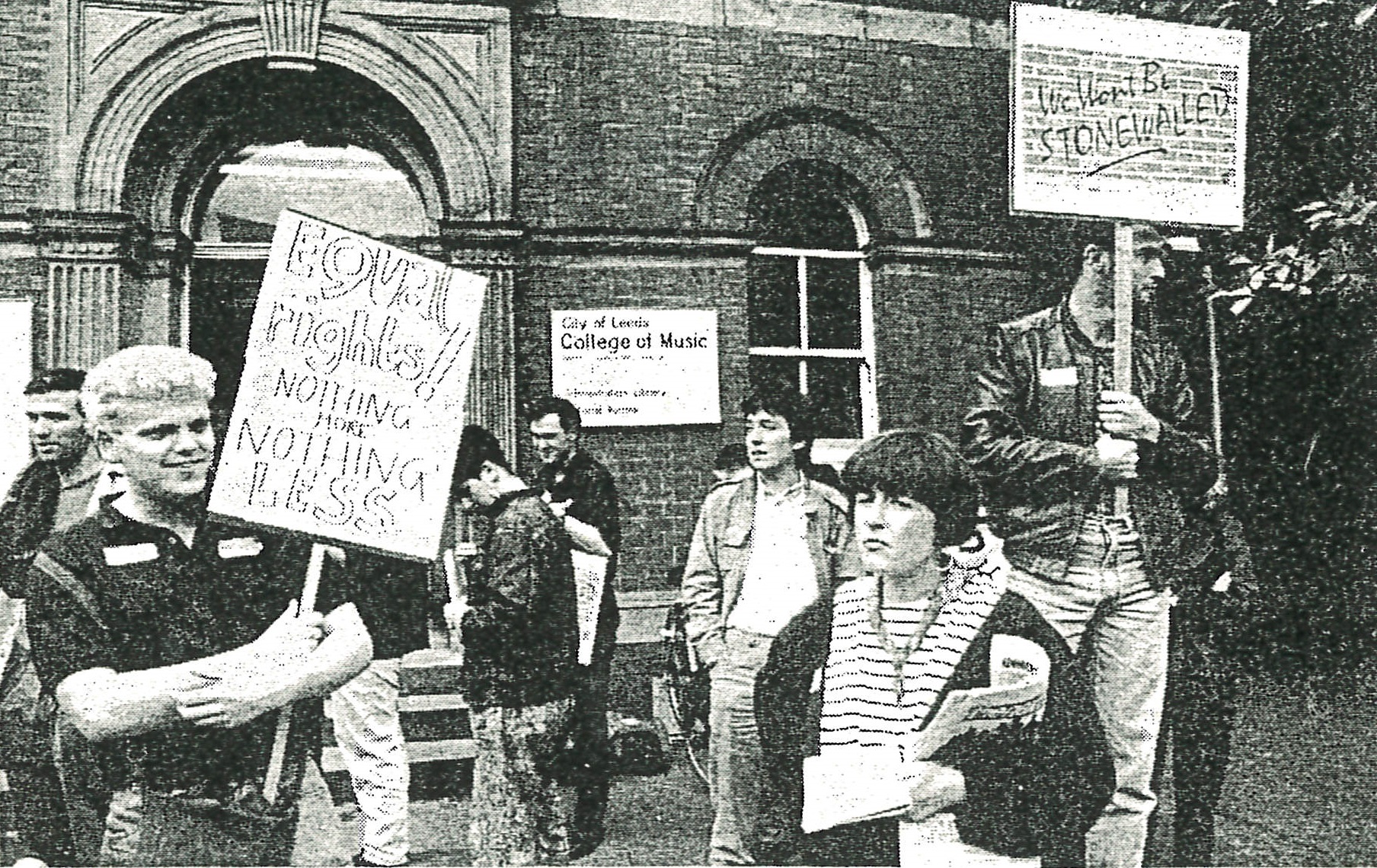 Old newspaper photo of people with placards protesting for equal rights outside Leeds College of Music.