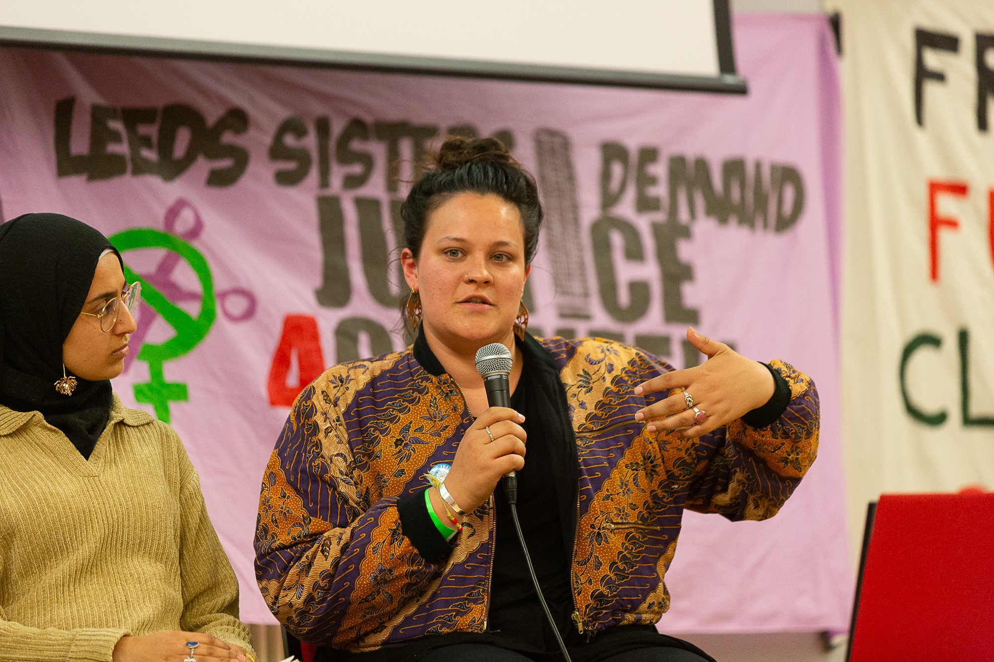 Coralie holds a microphone and speaks at a conference event