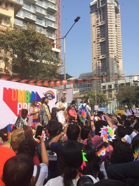 Performers stand in front of a rainbow sign that reads MUMBAI PRIDE